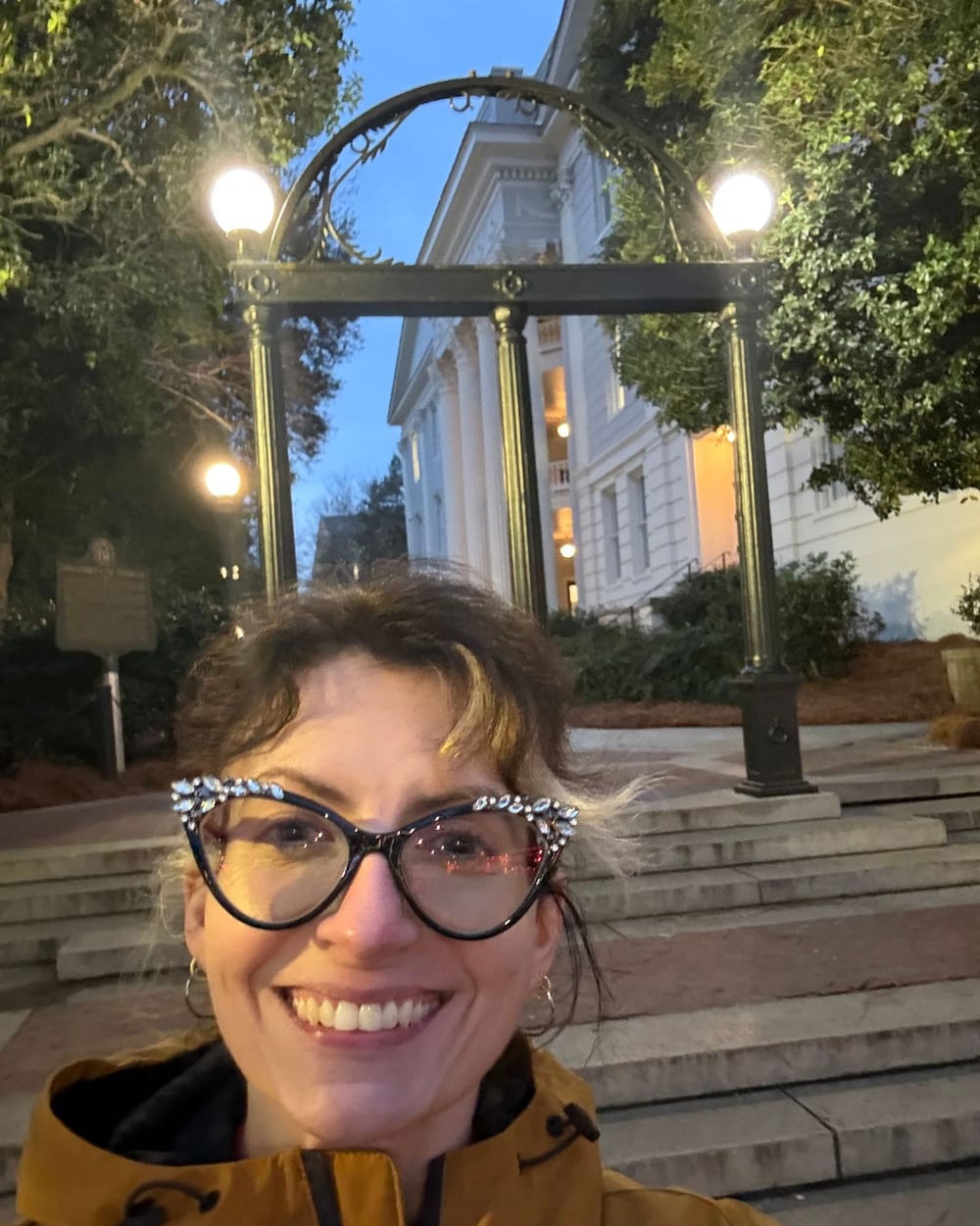 Sam smiling beneath the University of Georgia Arch at dusk