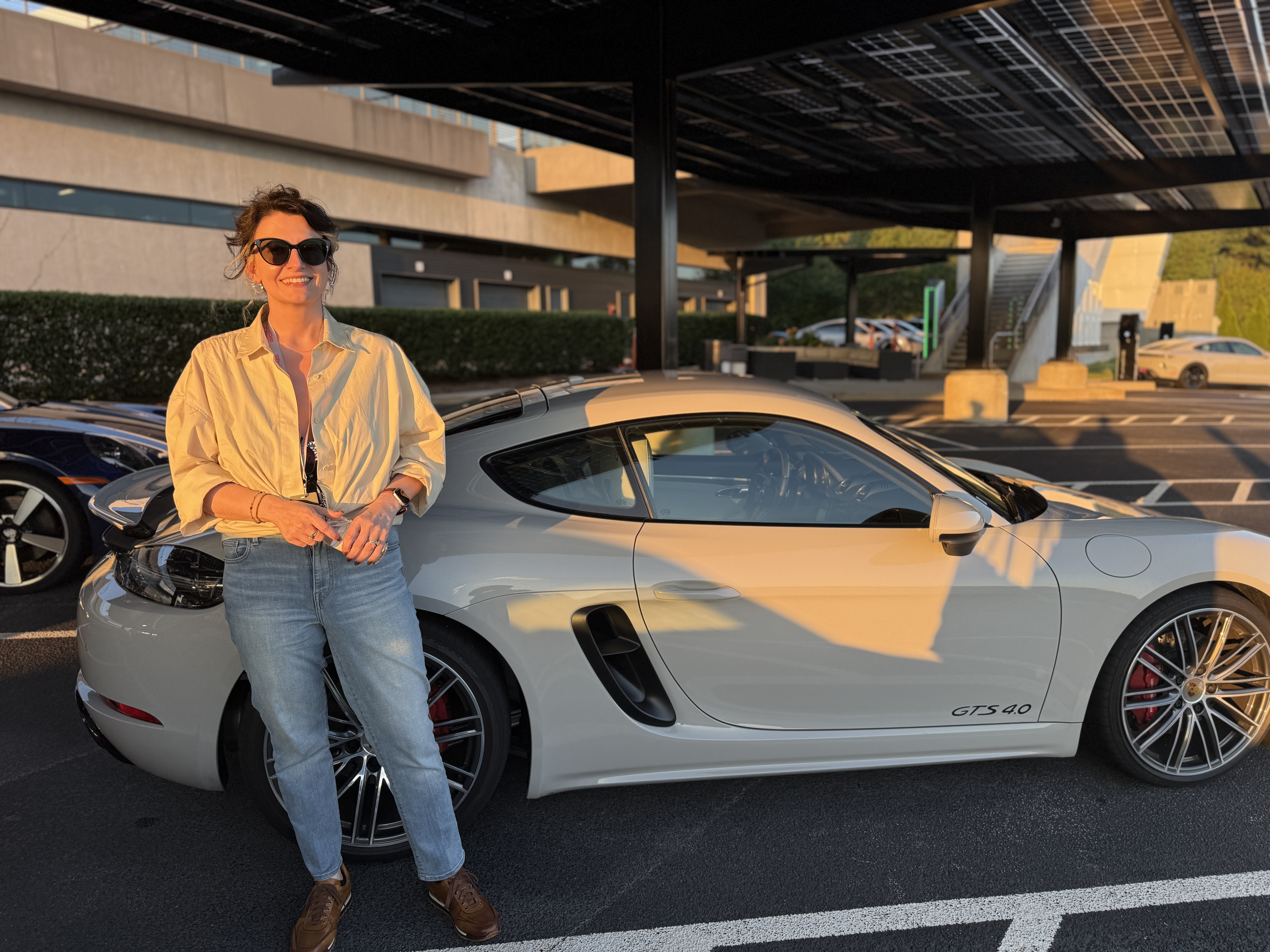 Sam beside a white Porsche Cayman GTS